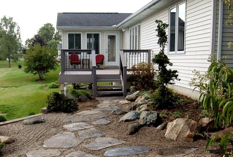 Boulder and stone planting — Boulders and natural stone worked into a planting bed beside a raised deck.