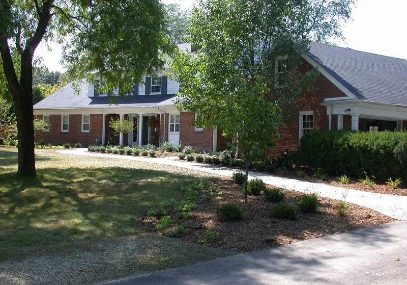 Drive-side landscape — Planting and mulch beds carried along a curved drive at a brick colonial.
