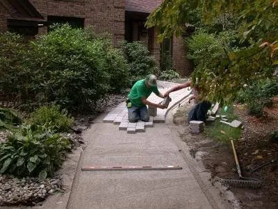 Quality Landscape crew screeding bedding sand and setting pavers by hand
