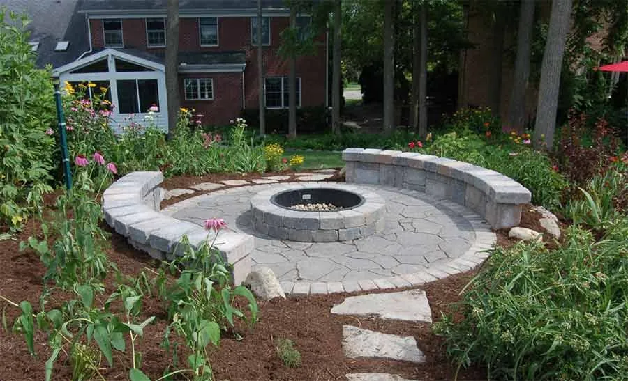 A stone fire pit ringed by a curved seat wall and perennial planting