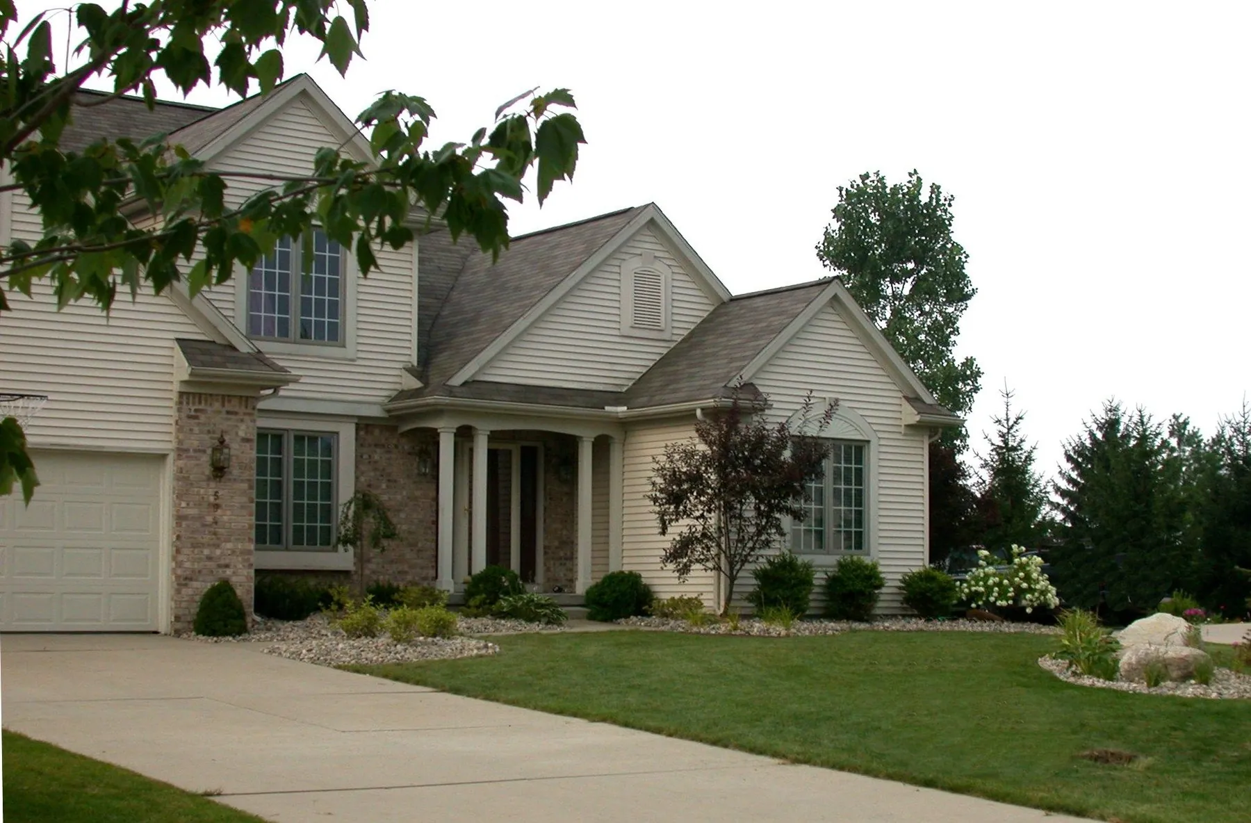 A Greater Lansing home with foundation plantings, mulched beds, and a maintained lawn installed by Quality Landscape, Inc.
