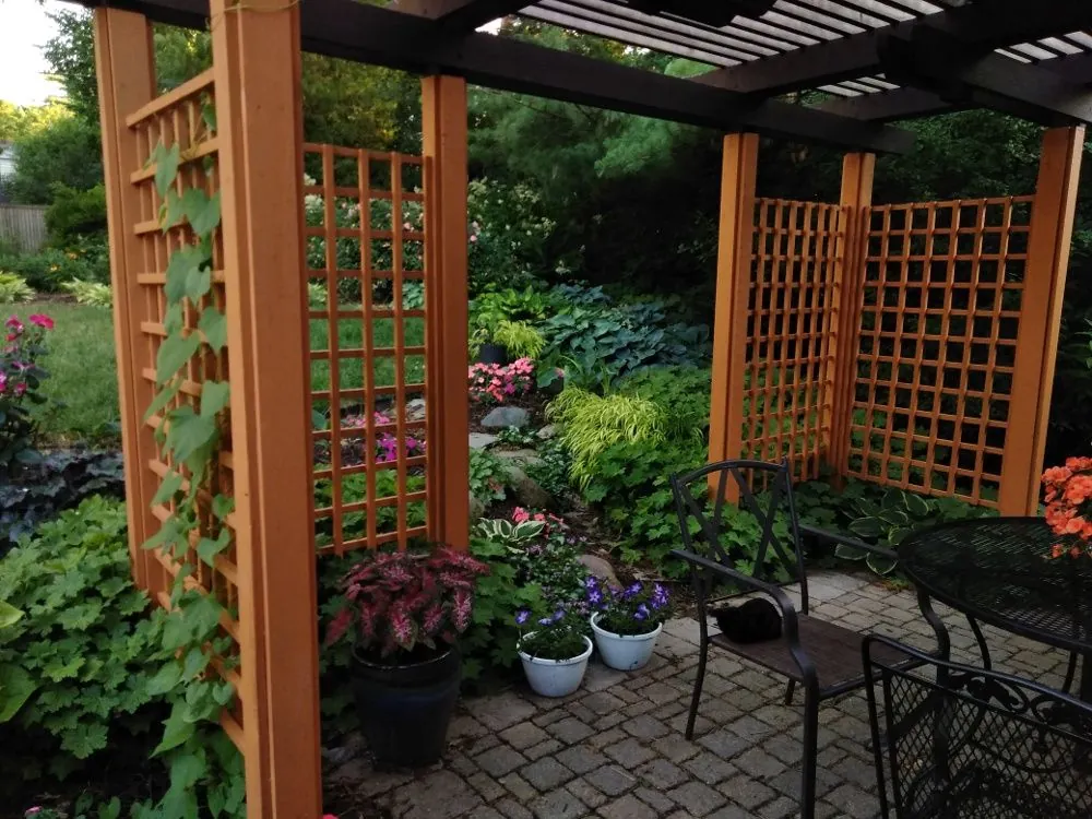 A cedar pergola over a paver patio with container plantings