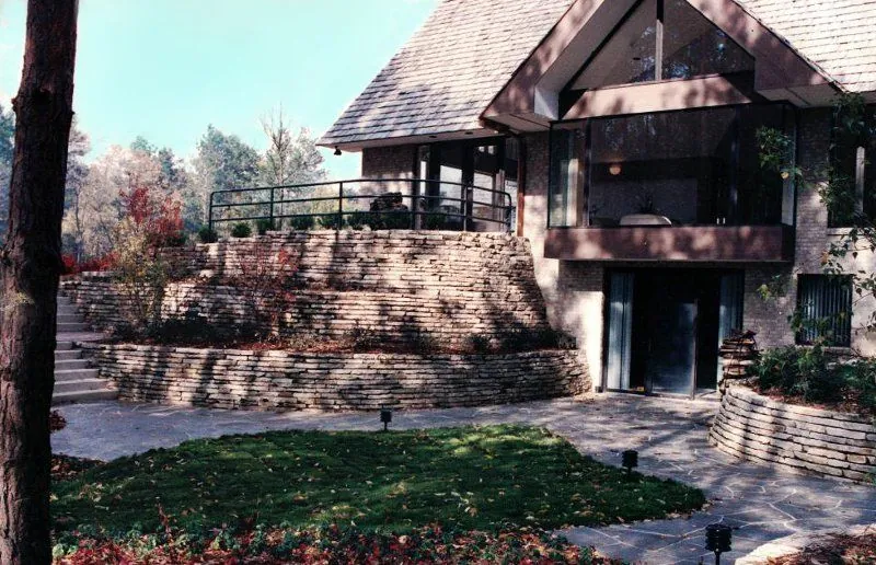 A tiered retaining wall holding a landscaped hillside below a home