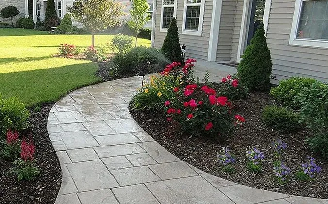 A curving paver walkway edged with roses and perennials, installed by Quality Landscape